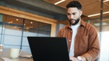 Man works on laptop computer with coffee