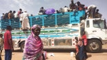 Refugees board bus to escape Sudan violence.
