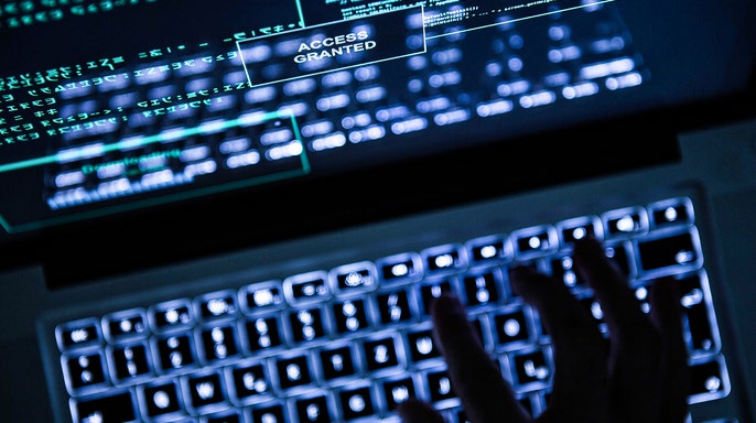 Hacker typing on a laptop.