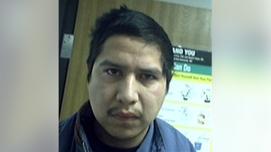 Man looks at the camera in a close-up indoor photo near a wall poster.