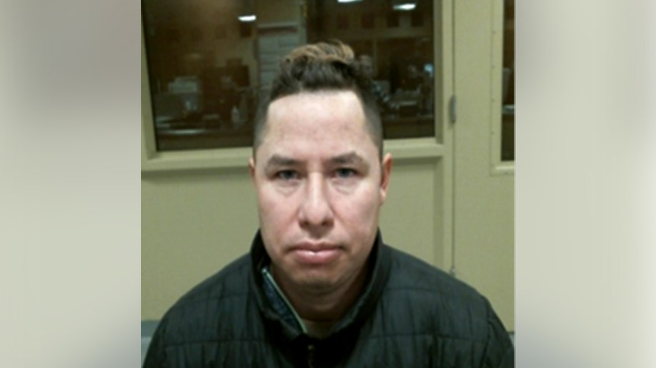 Man faces the camera in an indoor room with a large window behind him.