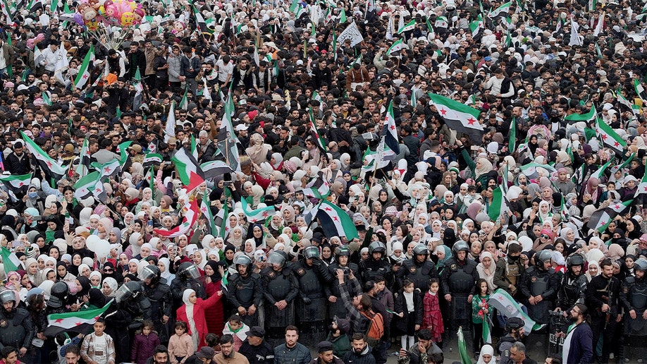 Crowds gather in a central Damascus square during a public celebration marking a political anniversary.