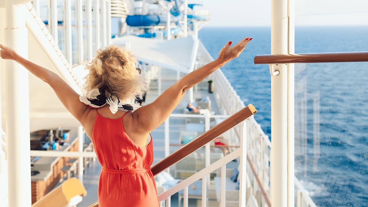 Woman with arms outstretched aboard cruise ship.