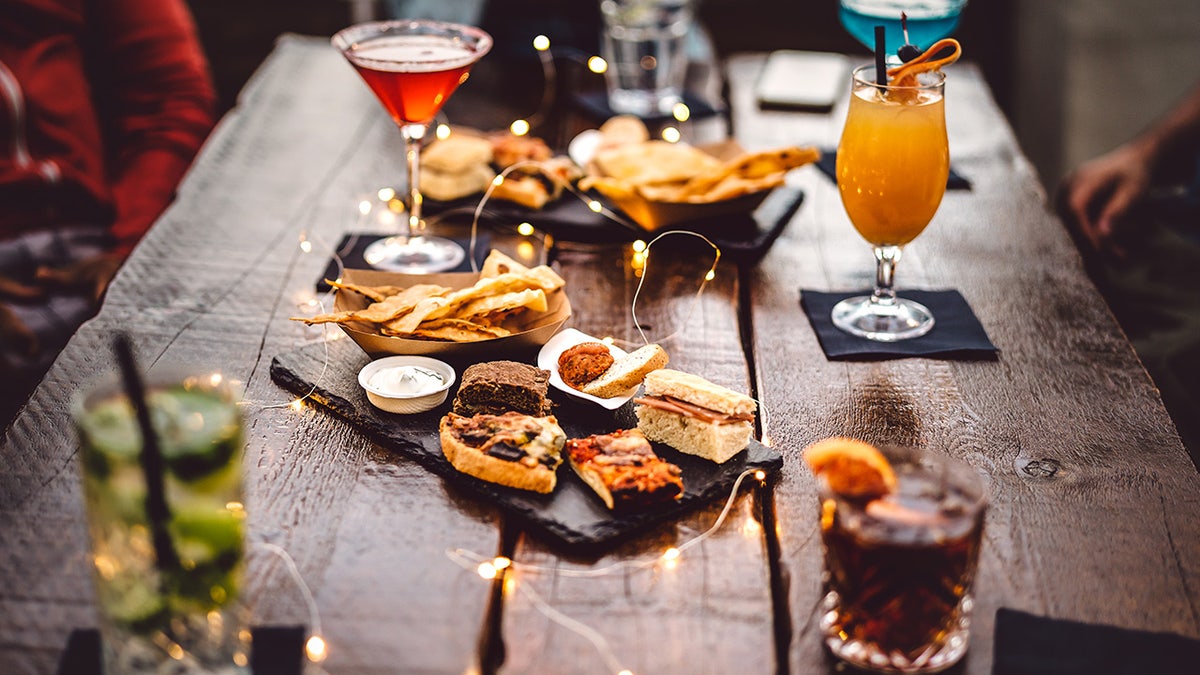 Array of different alcoholic beverages on table at restaurant with apps in the middle.