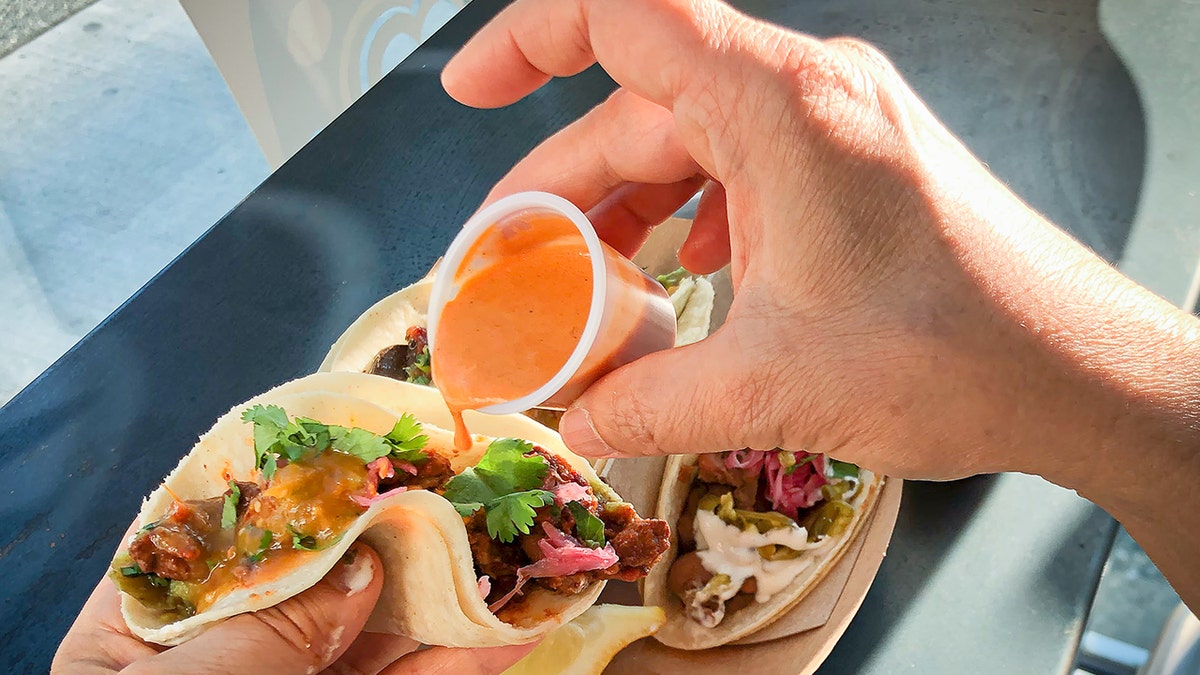 Man pouring hot sauce on taco