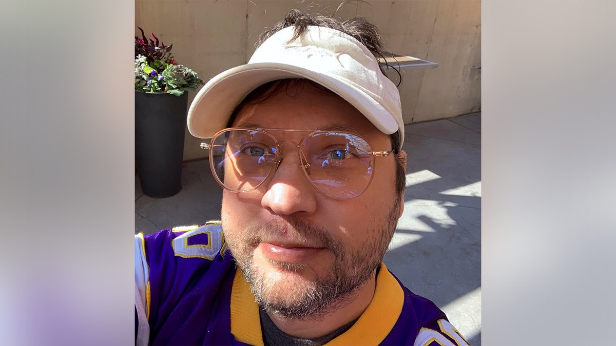 Anthony James Kazmierczak takes a selfie while wearing glasses and a white visor.