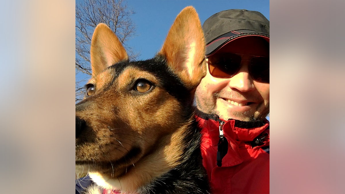 Anthony James Kazmierczak smiles next to a dog while taking a selfie.
