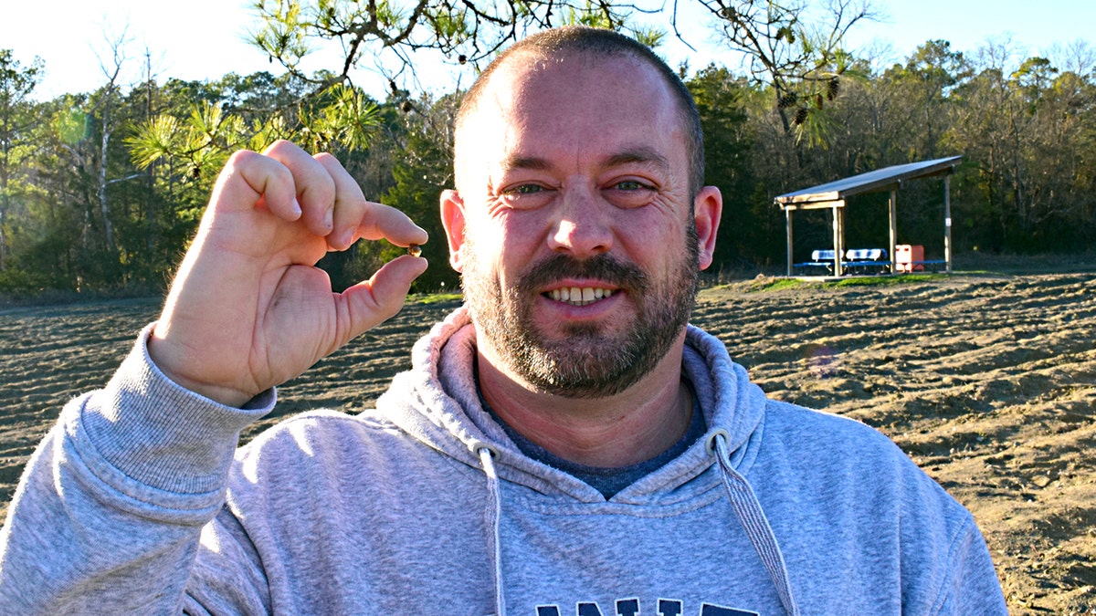 Man smiles while holding brown diamond