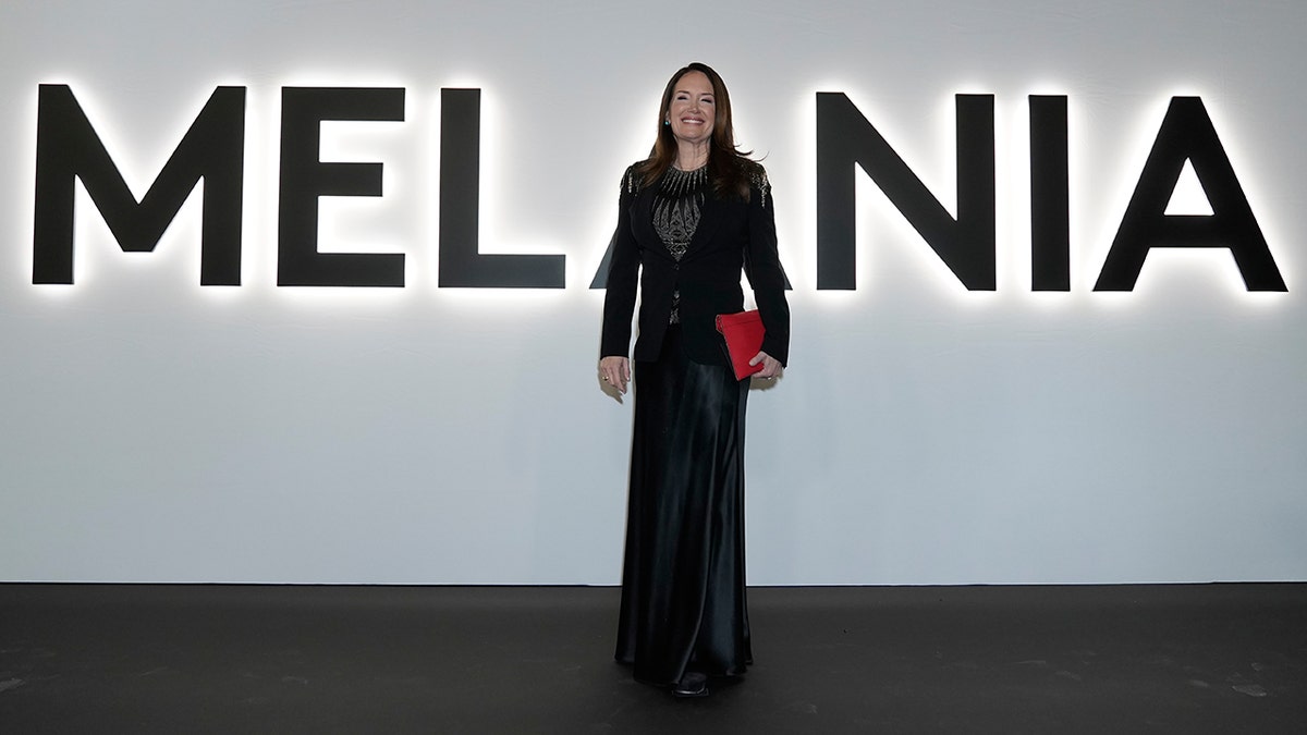 Brooke Rollins wearing a black embellished dress and blazer and holding a red clutch at the red carpet "Melania"