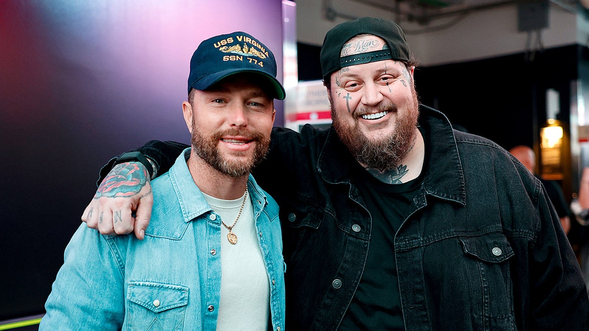 Chris Lane and Jelly Roll stand together backstage at a music festival.