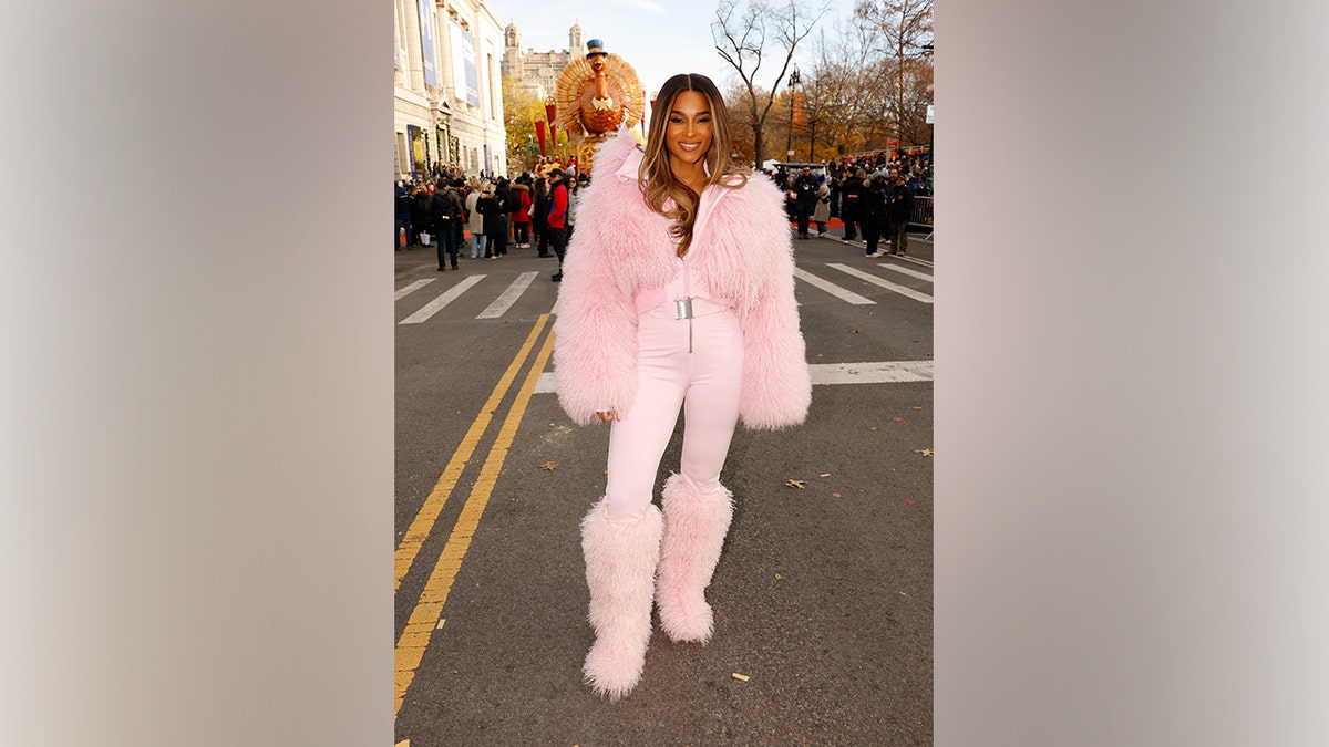 Ciara wearing a bright pink fur-trimmed Cordova ski outfit with matching boots at the Macy’s Thanksgiving Day Parade in New York.