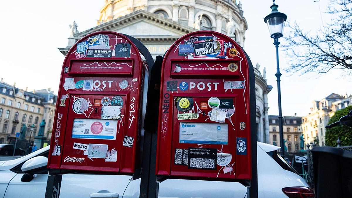Two red mailboxes are shown in front of a church in Copenhagen, Denmark.