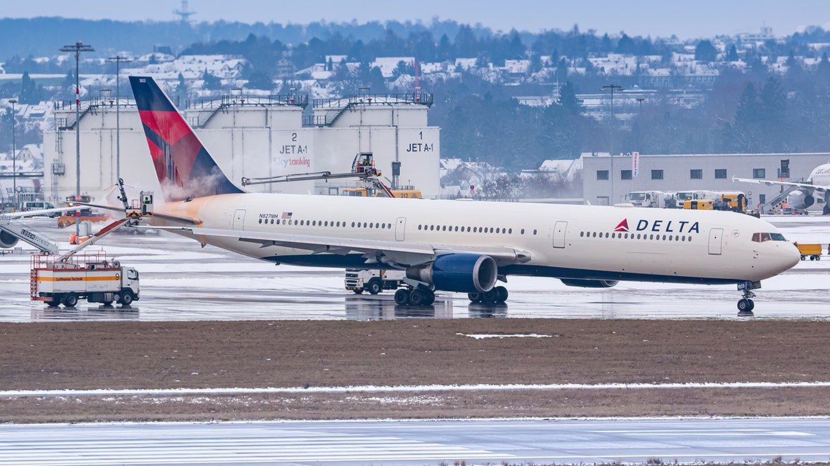 Delta Air Lines wide-body planes are de-iced from icy airport tarmac during winter operations.