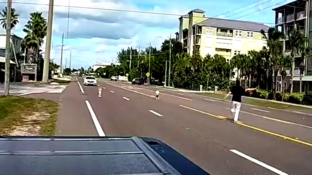 John Brittingham holding up hand to stop traffic as he runs toward children in the road
