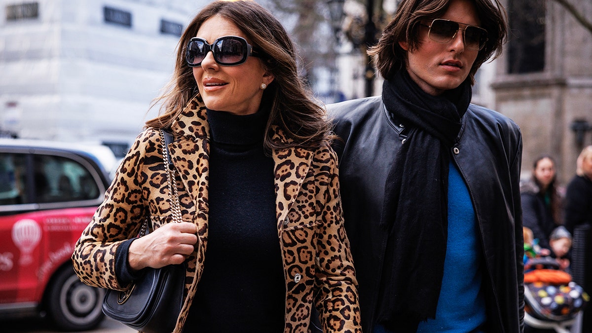 Elizabeth Hurley wearing a leopard coat and a black dress walking next to her son as they head to court in London.