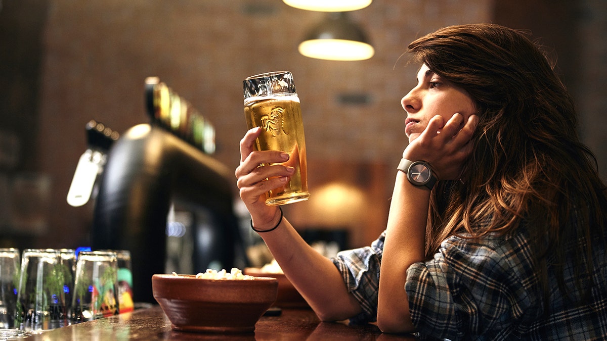 Unhappy woman looking at beer in bar