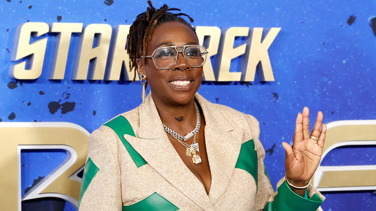Gina Yashere poses for photographs while standing at a red carpet premiere event.