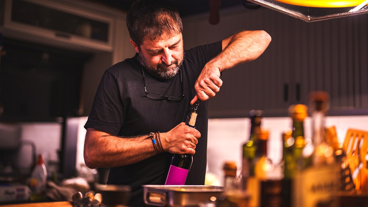 Older man opening bottle of wine