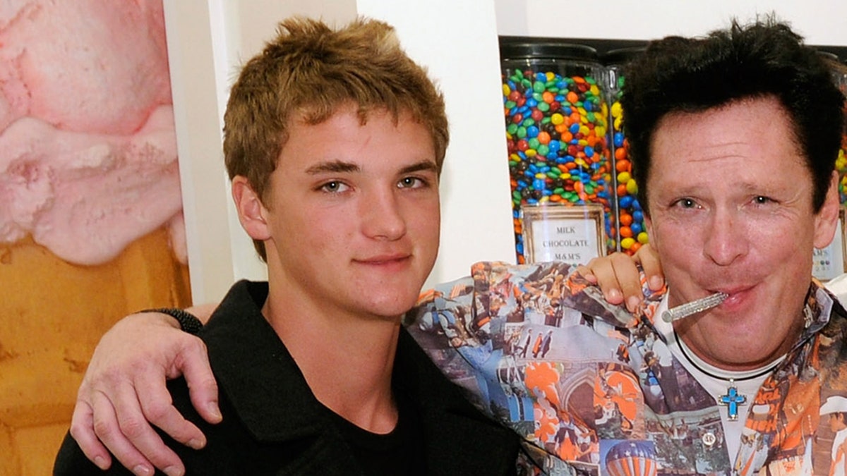 Michael Madson smiling and enjoying a lollipop while embracing his son Hudson.