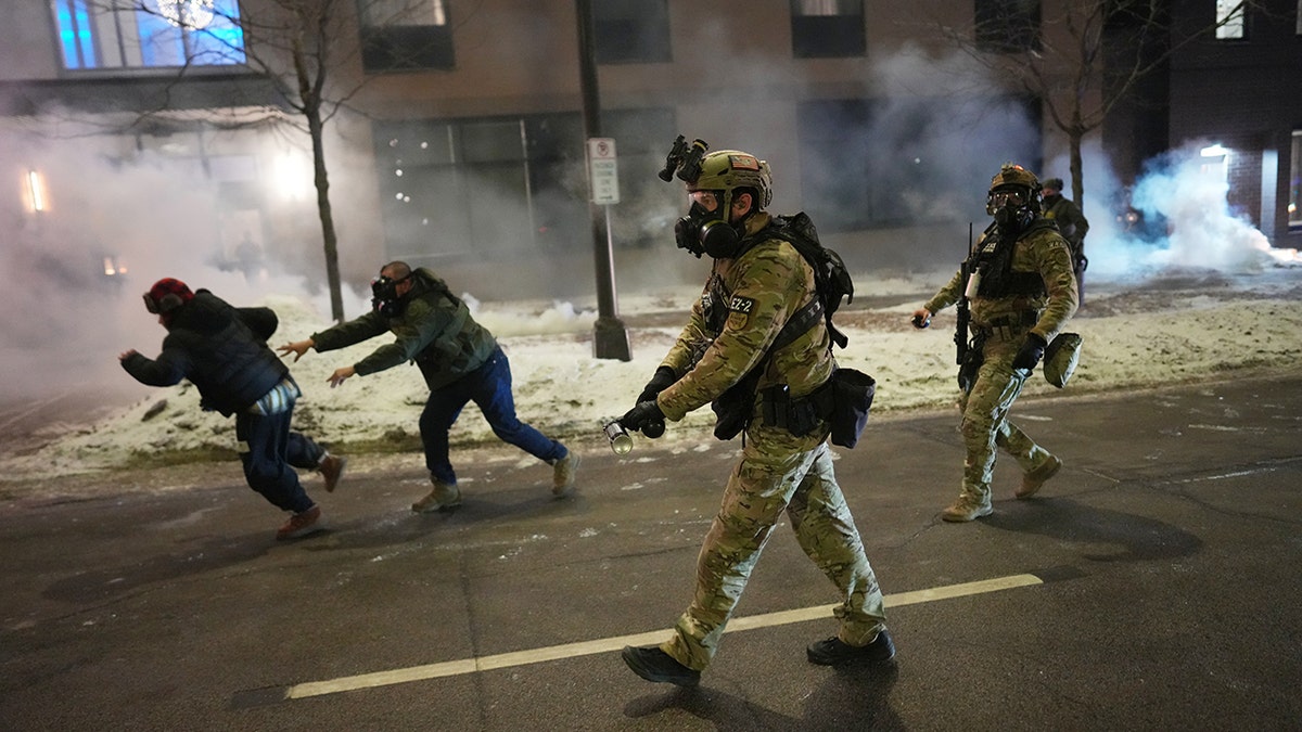 Federal agents standing in a cloud of tear gas near a hotel while clearing demonstrators.