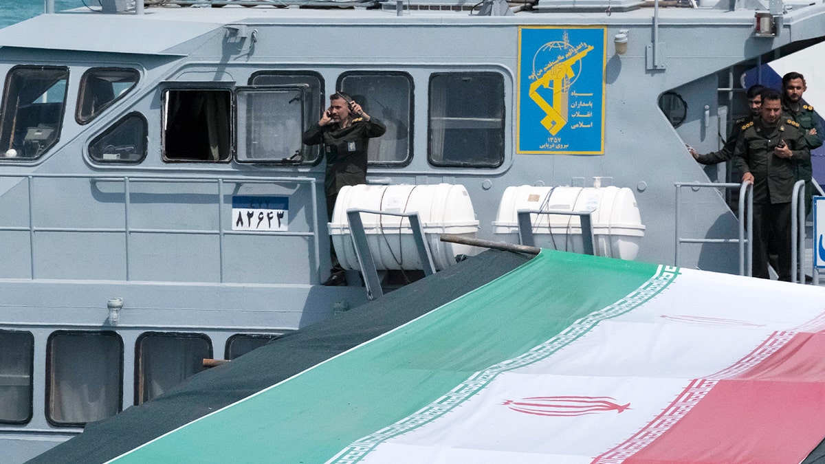 Uniformed naval personnel stand on the deck of a military vessel during a parade.