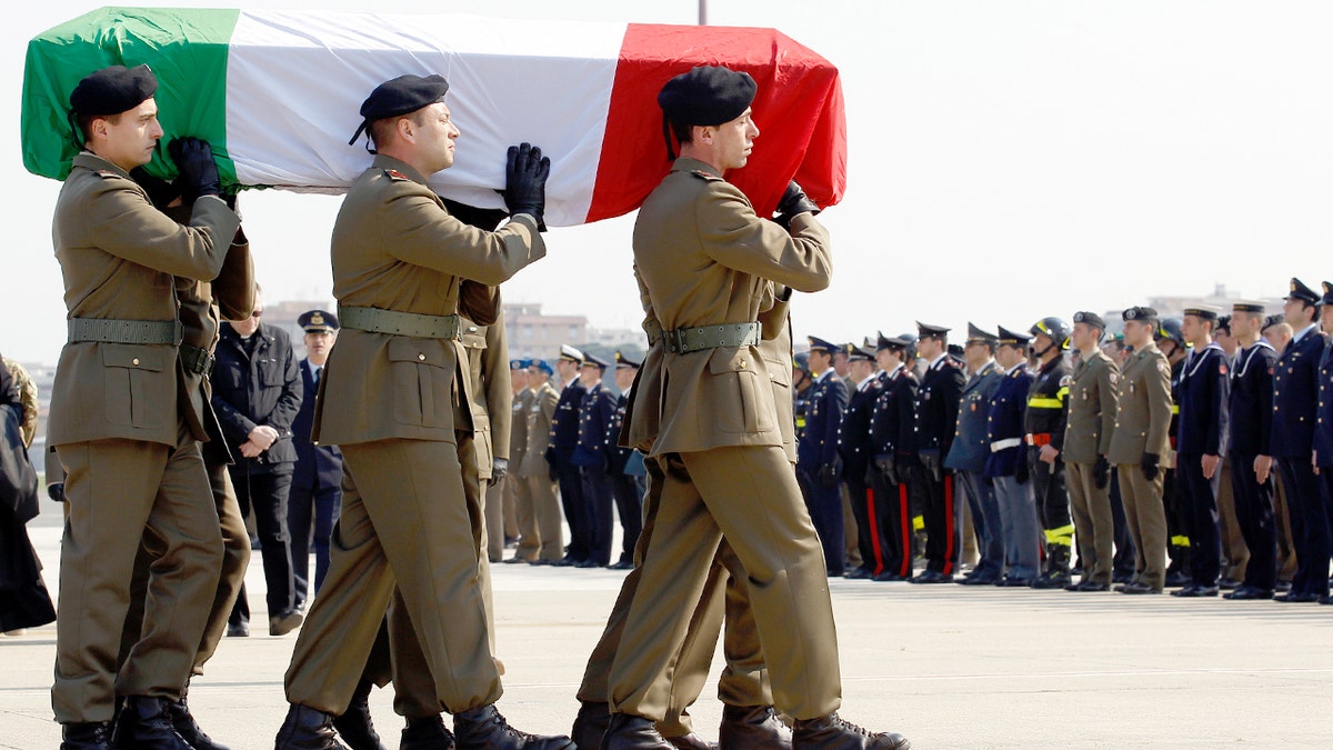 Soldados italianos carregam um caixão coberto com a bandeira da Itália em um aeroporto