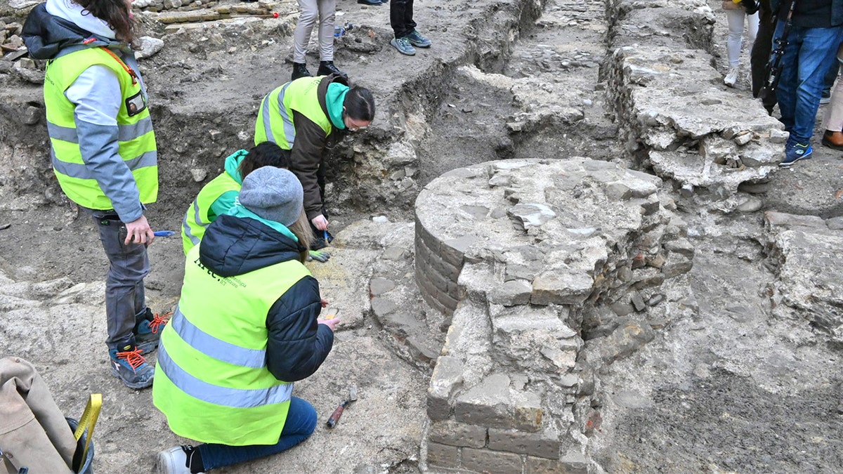 Archaeologists hunched around brick structure