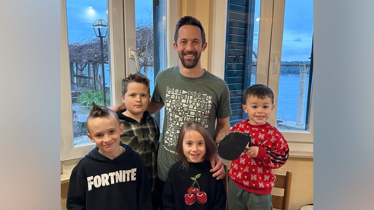 A father poses with four children in a family photo.