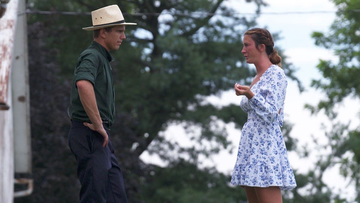 Kendra Bates wearing a blue and white dress being emotional in front of James while filming "Suddenly Amish."