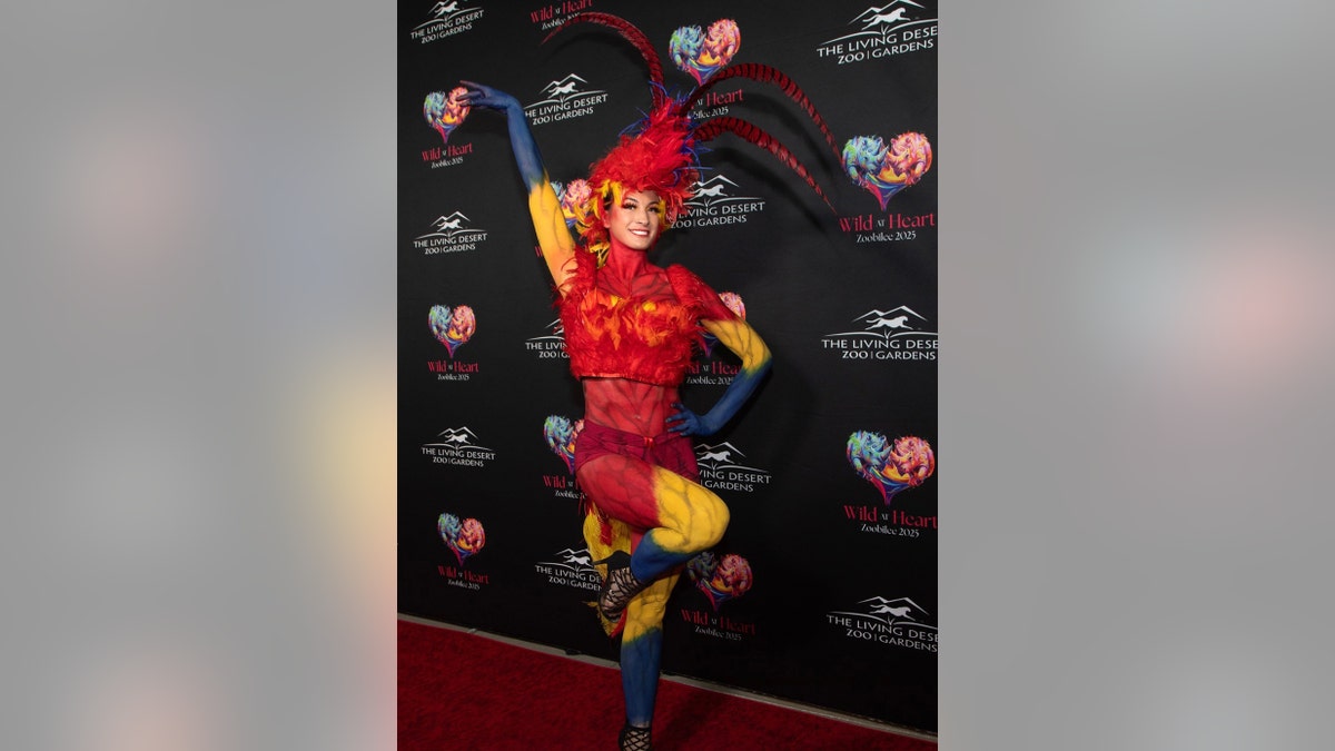 Kendra Bates in a red and yellow costume at a step and repeat.