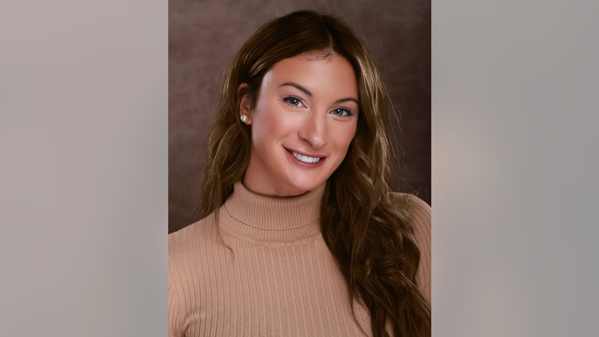 Kendra Bates wearing a tanned turtleneck sweater and smiling with her hair down.