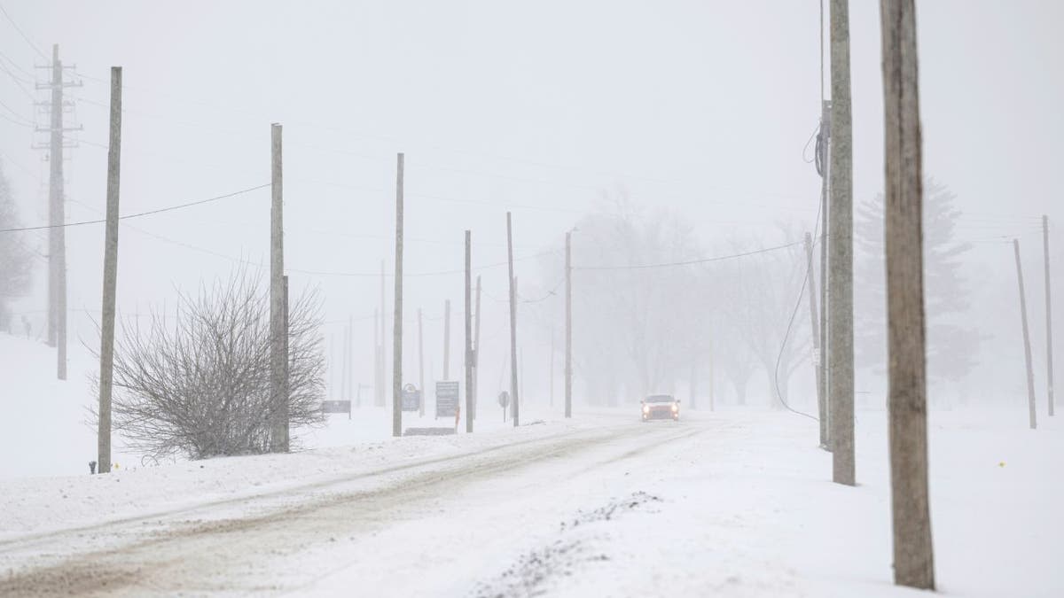 A vehicle driving on a snow-covered road during a winter storm in Kentucky
