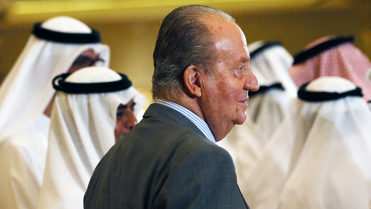 King Juan Carlos in a grey suit looking away.