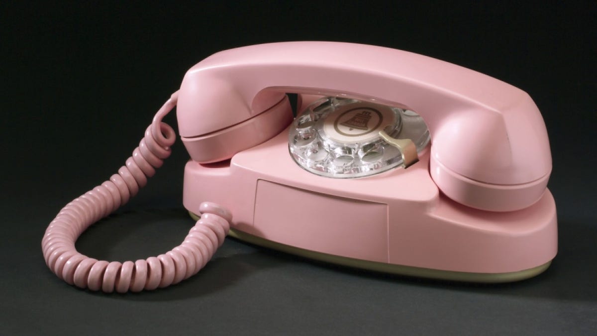 A pink landline phone is pictured on the table.