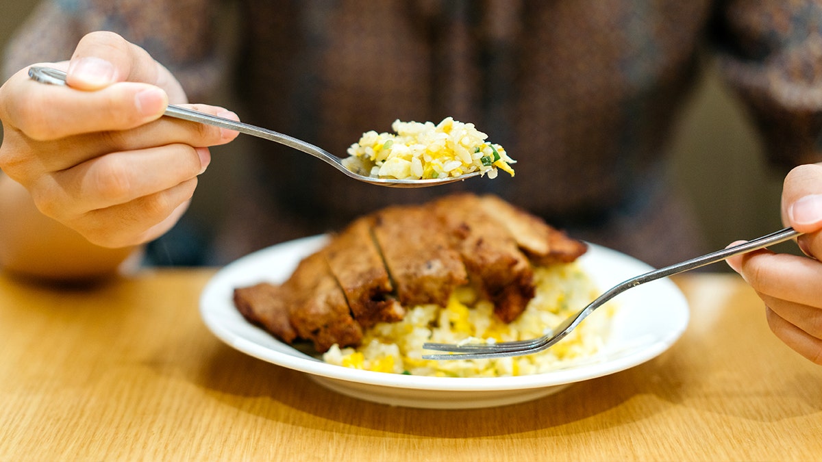 Woman eating rice and pork chop