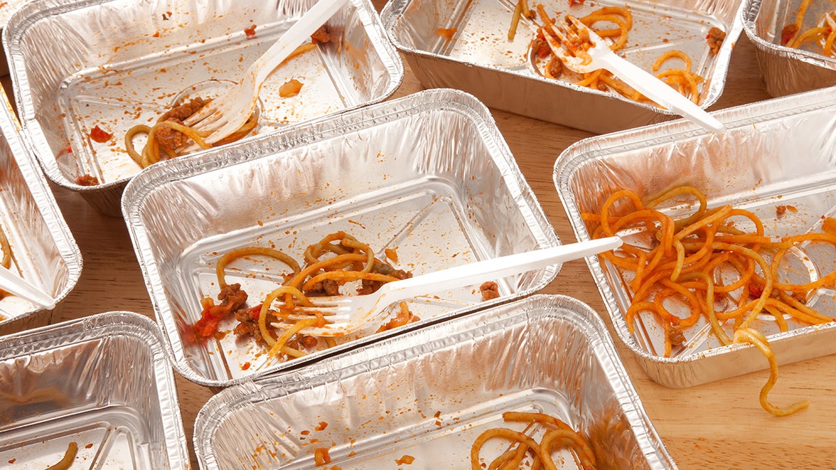 Takeout containers of pasta that was mostly eaten, with plastic forks still scattered about.