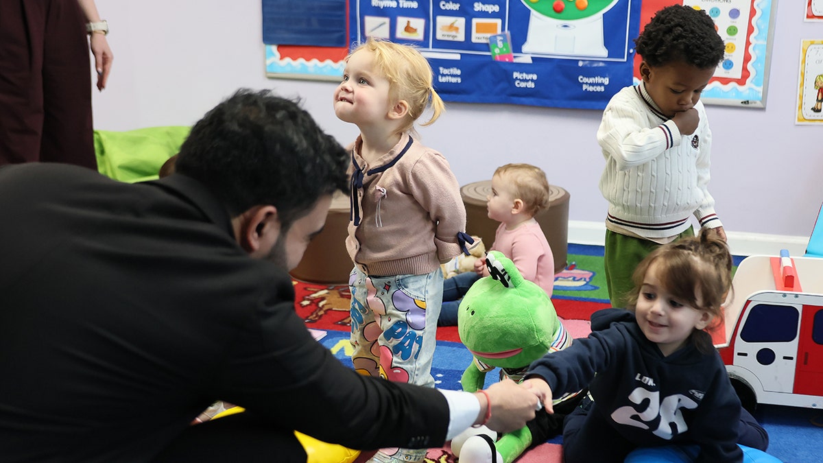 Mamdani shaking a child's hand at a school