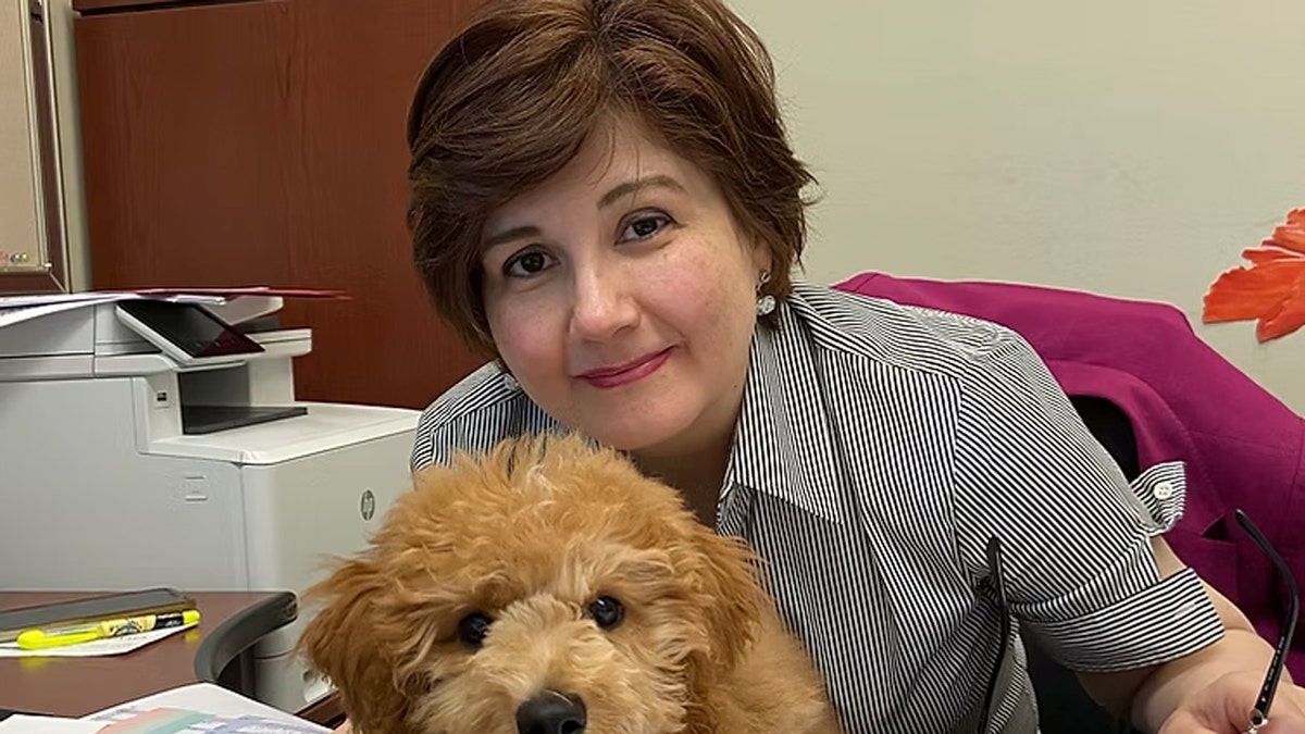 Aryan Papoli holding a dog at a desk
