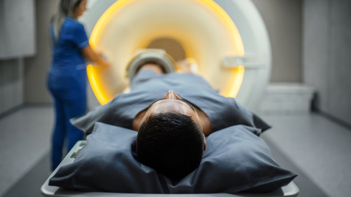 Patient entering MRI machine as technician starts procedure