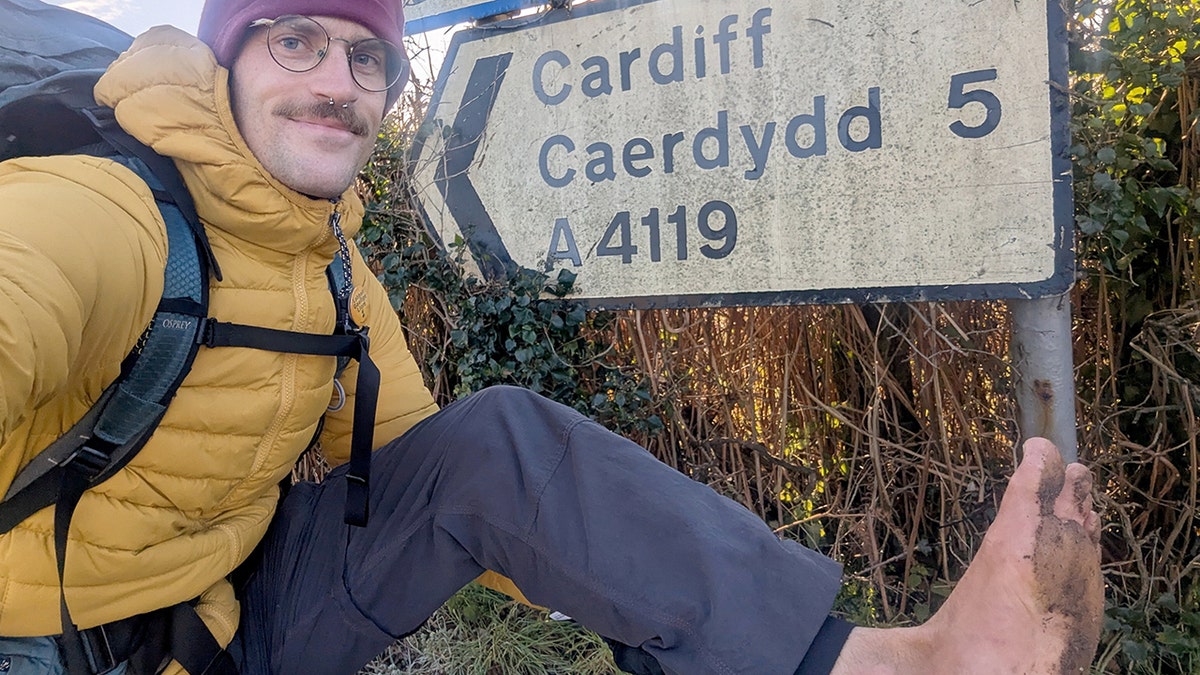 Eamonn Keaveney connected  his barefoot travels holding up   his dirt-covered ft  astatine  a landmark.