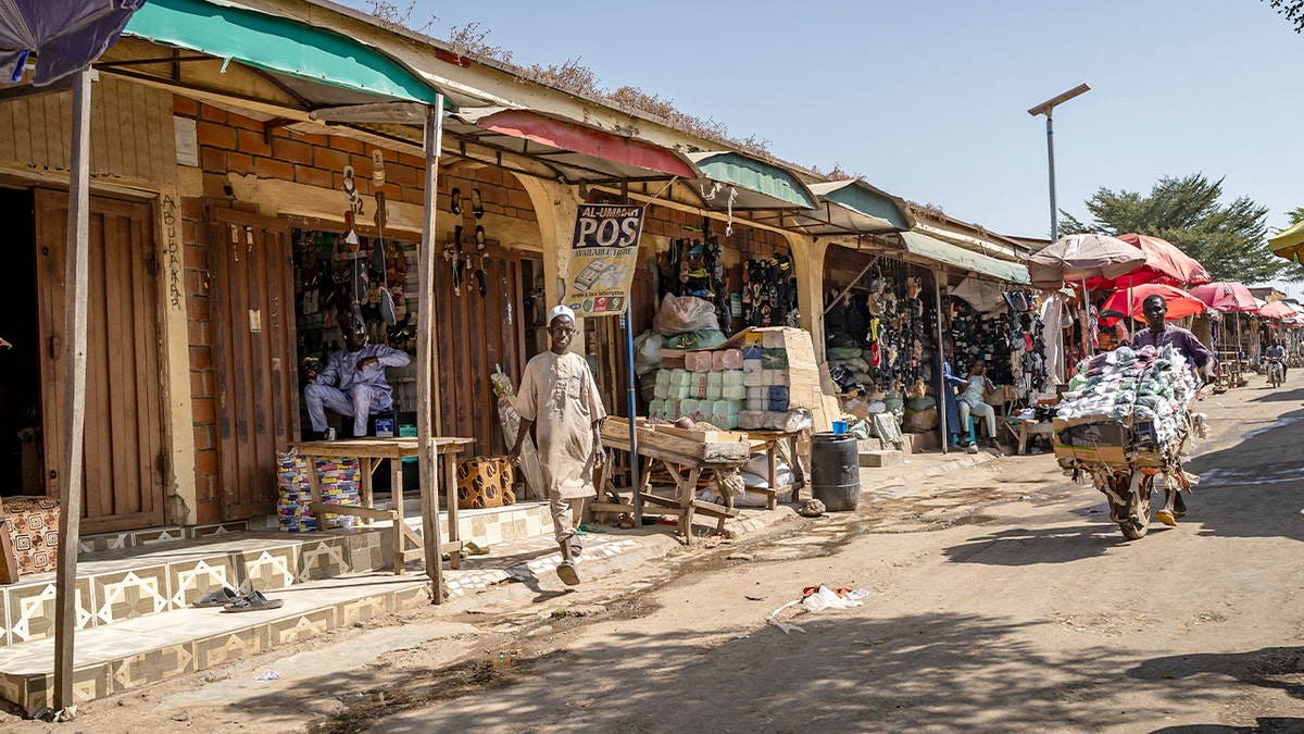 Open-air market stalls and shoppers fill a busy commercial area.