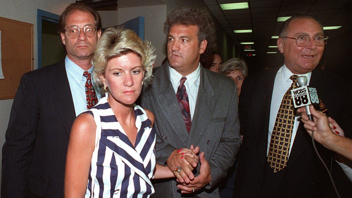 Mary Jo Buttafuoco holding onto Joey Buttefuoco's hand wearing a striped navy and white blouse.