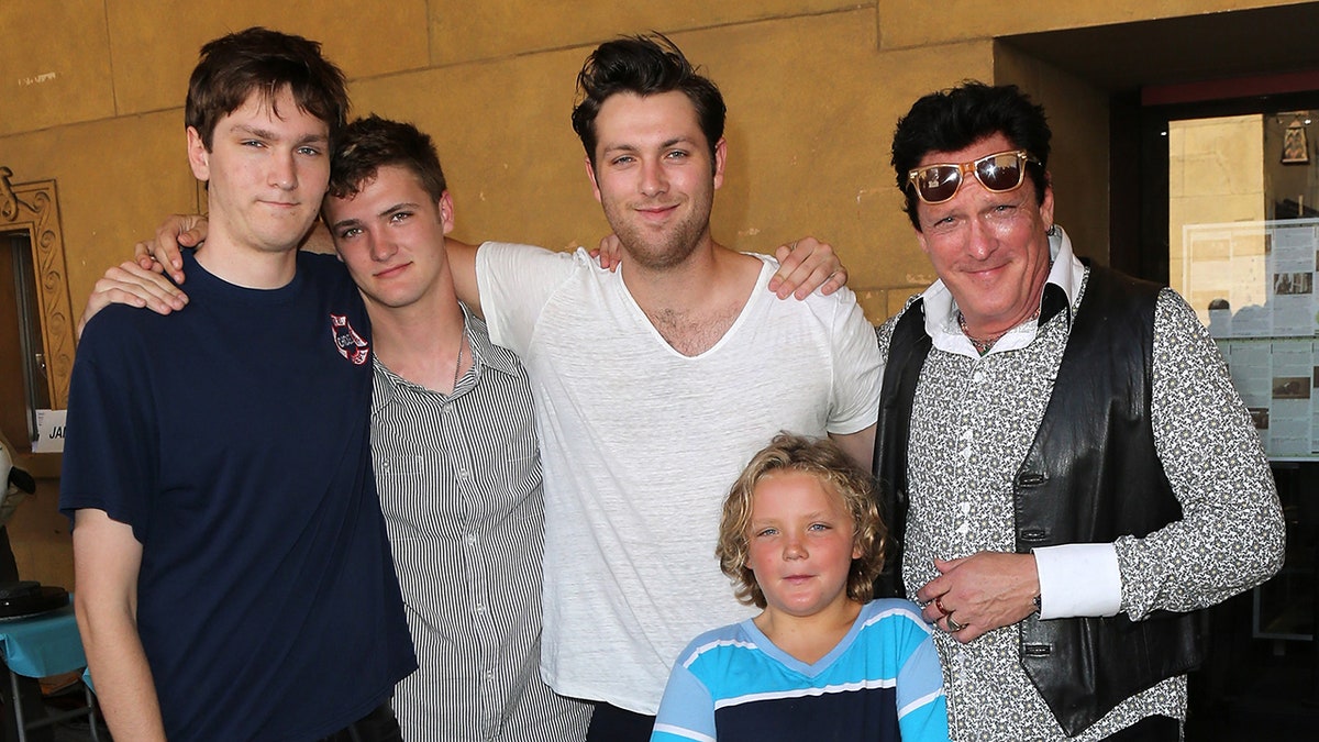 Michael Madson smiling while posing with his sons.