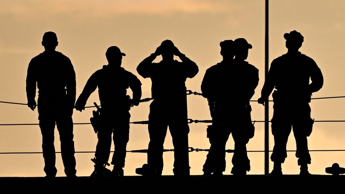 U.S. military personnel stand on the deck of the USS Iwo Jima at sunset in Puerto Rico.