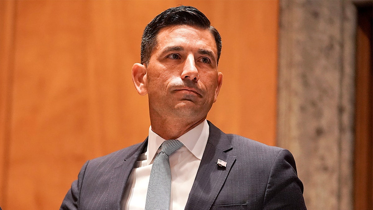 El secretario interino de Seguridad Nacional levanta la mano derecha mientras presta juramento ante una comisión del Senado.