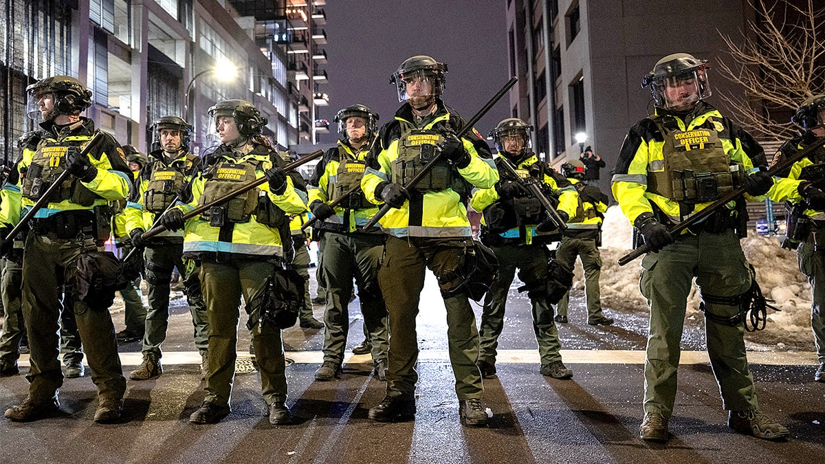 Law enforcement officers move protesters away during a confrontation outside hotels believed to house federal agents.