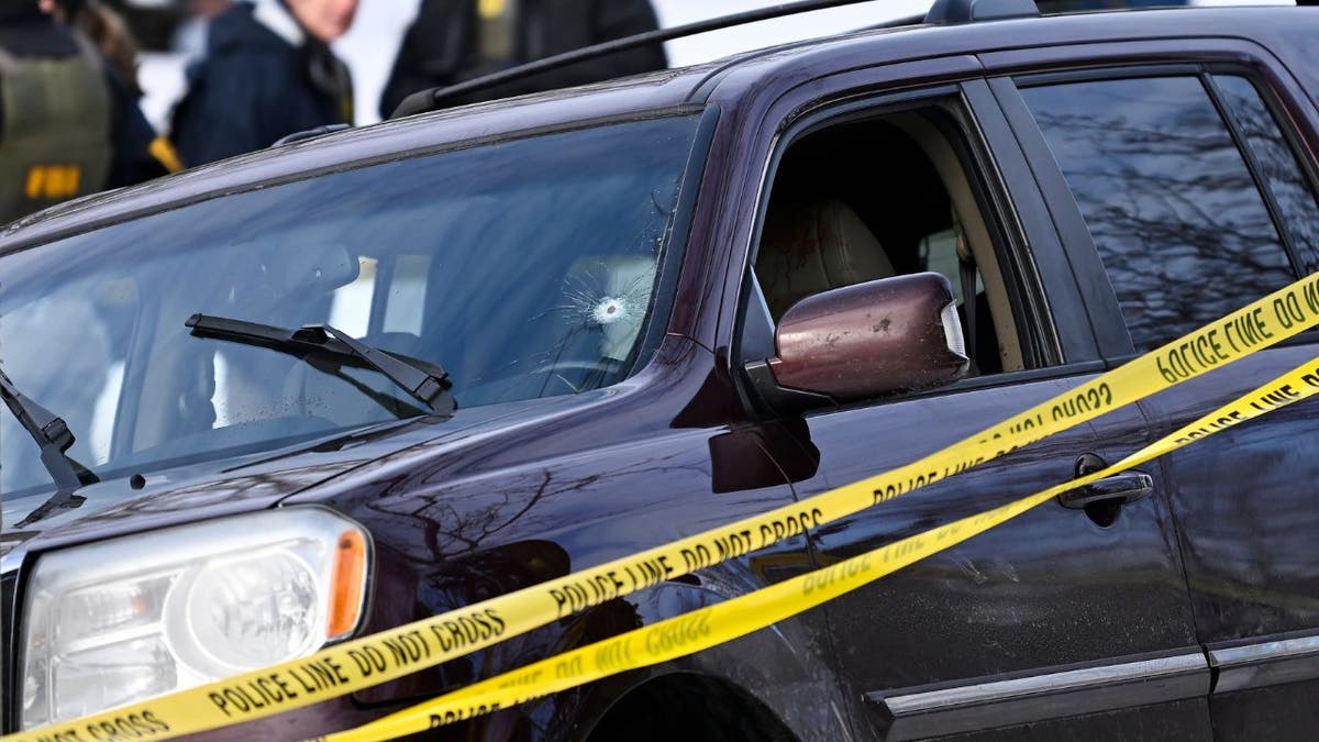 A vehicle with a bullet hole in the windshield sits behind police tape at a crime scene in Minneapolis.