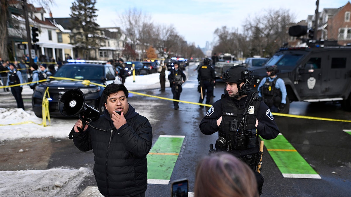Minneapolis City Council member Jason Chavez speaks from a megaphone