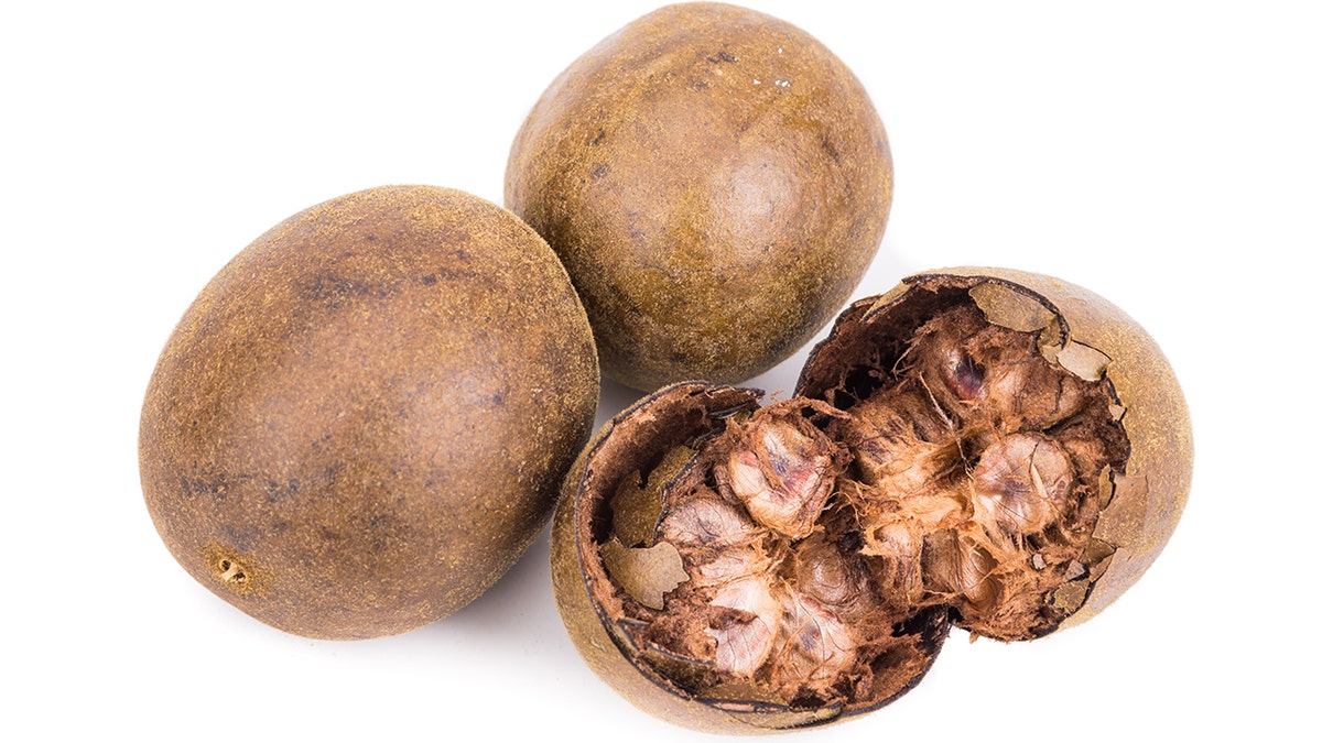 Monk fruit seen up close, one cracked open to show hard shell and fleshy, pulpy fruit insides.