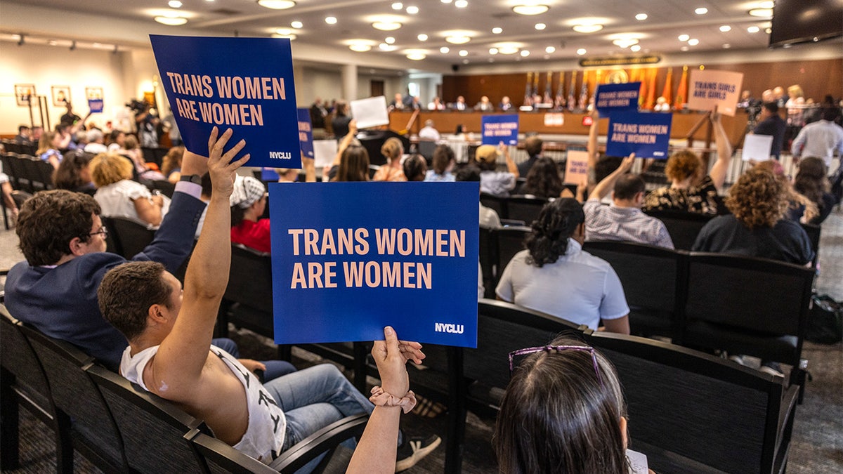Protesters hold signs reading 